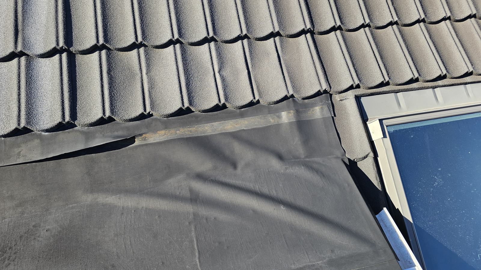 Butynol membrane lifting and loose where a flat section meets a tiled roof and skylight