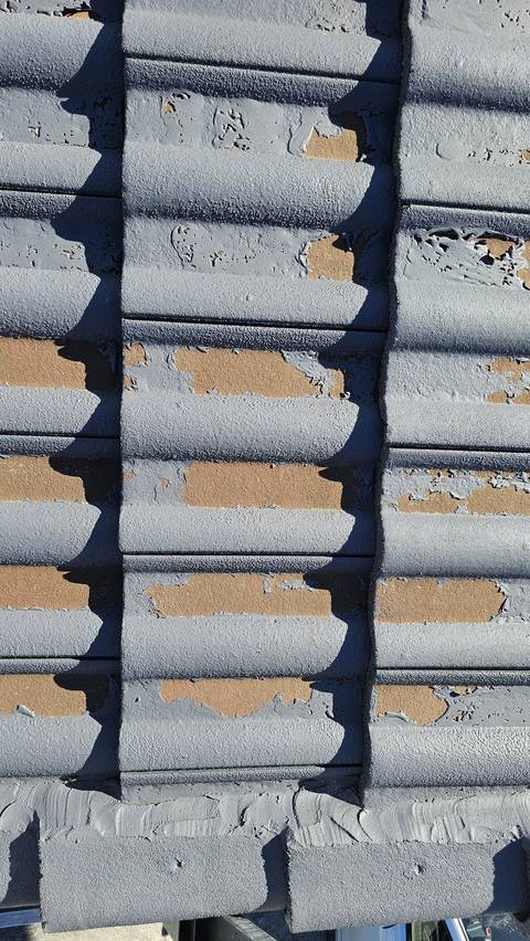 The applied coating is lifting and peeling in patches across these concrete tiles, exposing bare substrate underneath.