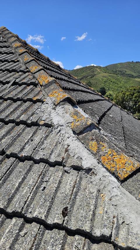 Fresh mortar has been smeared well beyond the hip junction and across the faces of the surrounding tiles.
