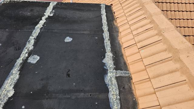 Lines of aged sealant follow the seams of this Butynol roof, marking earlier repair attempts that have weathered and broken down.