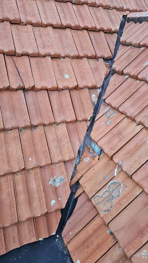 Beside the valley, terracotta tiles have cracked and slipped out of position, leaving the flashing and open gaps exposed.