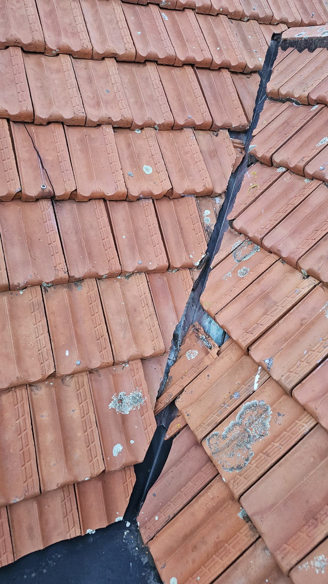 Terracotta tile roof with a cracked tile and a broken tile displaced over the valley junction