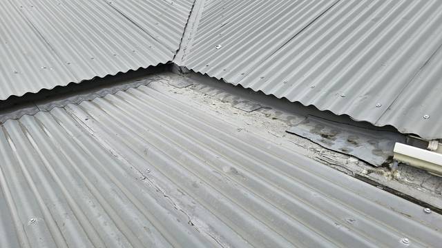 Several roof planes fall into a low-pitch section where the old flashings have been patched and the coating around them is cracked and lifting.