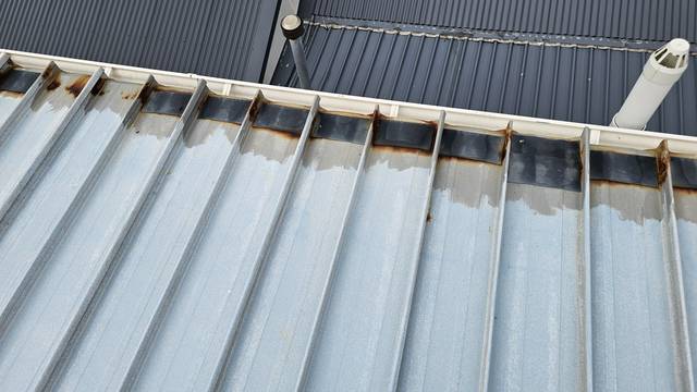 Rusted sections at the head of these steel trays have been patched with strips of Butynol membrane, with corrosion still visible around the edges.